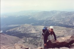 Jocelyn scrambling from the steep homestretch, with a valley in the background